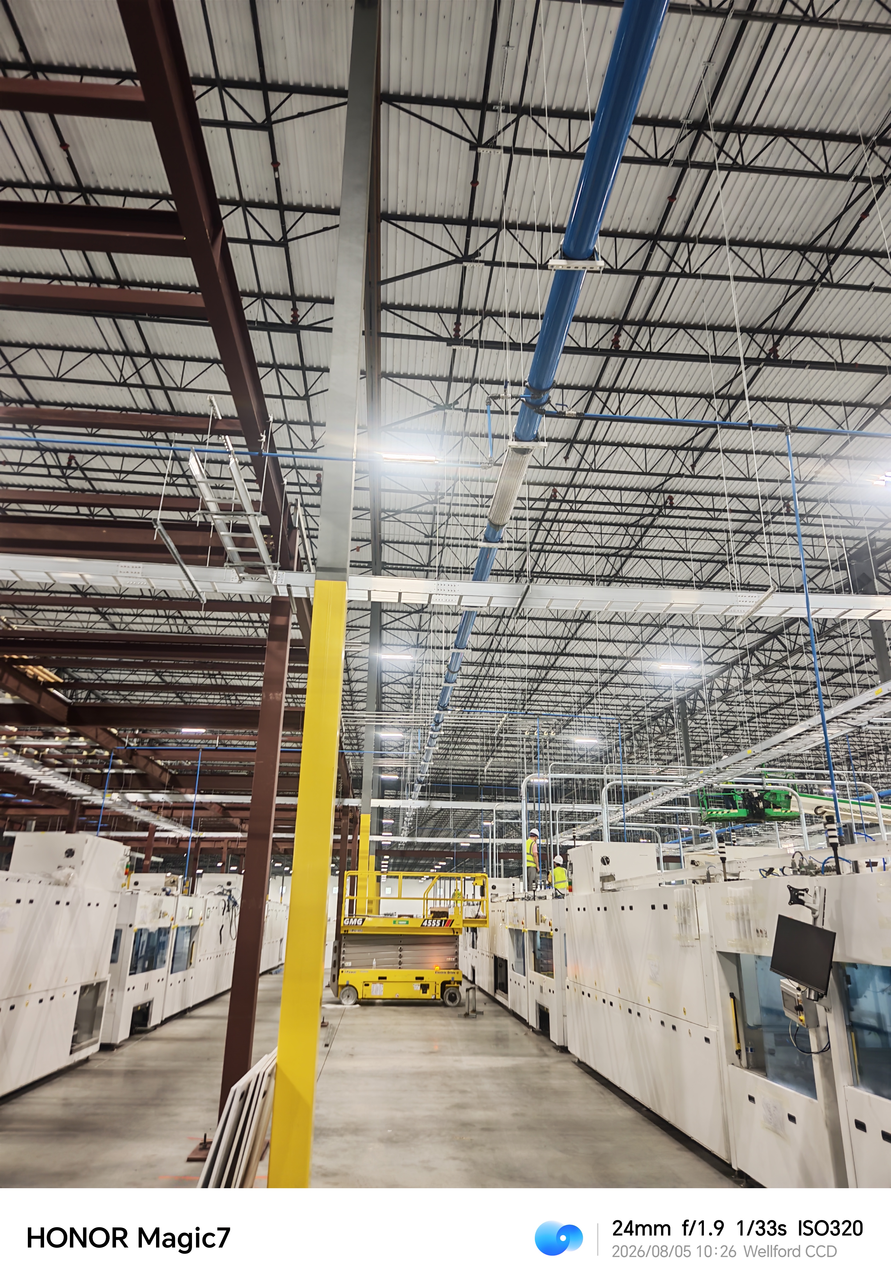 Interior de planta industrial con tuberías elevadas y personal de instalación